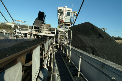 Moving conveyor of coal track loader  with stockpiles in background. - Mining Photo Stock Library
