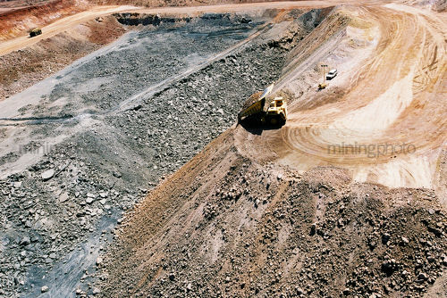 Haul truck emptying overburden onto stockpile in open cut coal  mine with light vehicle adjacent. - Mining Photo Stock Library