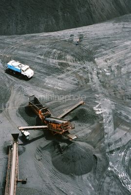 Quarry crusher with water cart and worker in background - aerial shot. - Mining Photo Stock Library