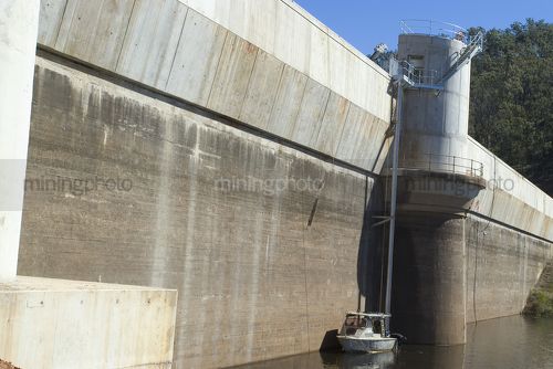 Australian dam wall with maintenance boat in the water.  shot from the side looking along the wall. - Mining Photo Stock Library