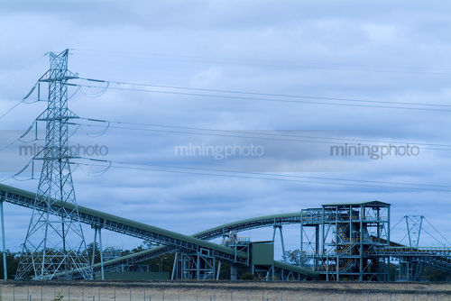 Coal conveyor at power station with electricity tower in background. suits landscape panorama.  blue wash through photo. - Mining Photo Stock Library
