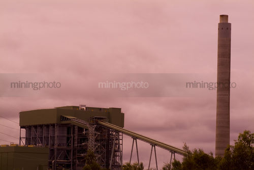Power station smokestack with plant and coal conveyors in background.  sunset shot. - Mining Photo Stock Library