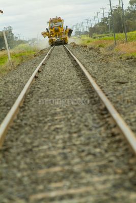 Looking along rail track at ground level to track maintenance in distance.  foreground track out of focus. - Mining Photo Stock Library