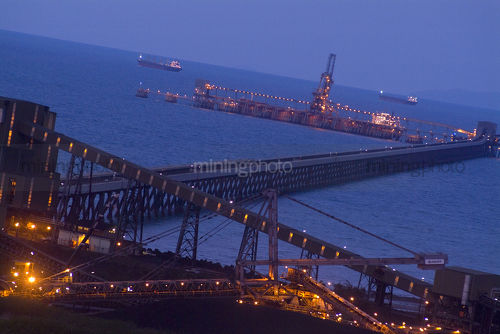 Coal terminal with long jetty out to wharf.  shot at sunset with ships in background out at sea. - Mining Photo Stock Library