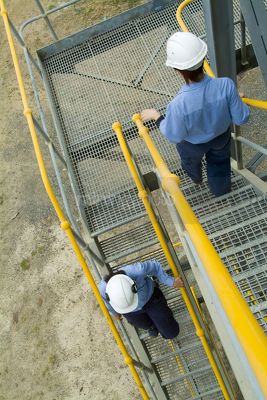 Female site engineers walking down stairs.  railings painted safety yellow - Mining Photo Stock Library