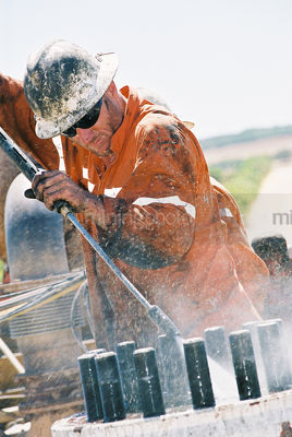 Male drill rig worker in safety PPE cleaning equipment with high pressure water cleaner.   - Mining Photo Stock Library