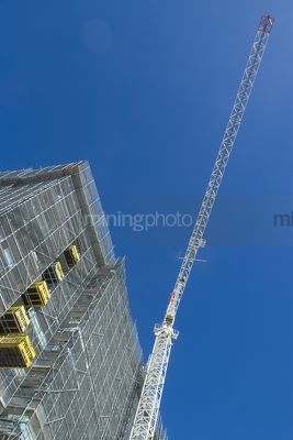 Tower crane at a multi level building site. deep blue sky behind - Mining Photo Stock Library