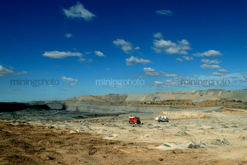Filling blasting holes at open cut coal mine.  coal seam, high walls and overburden stockpiles in background. - Mining Photo Stock Library