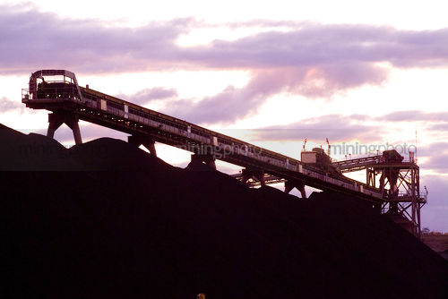 Coal conveyor stockpiling at mine site. shot at sunset - Mining Photo Stock Library