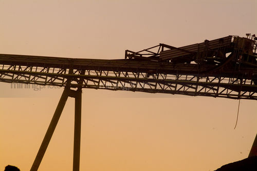 Coal conveyor stockpiling at mine site. shot at sunset - Mining Photo Stock Library
