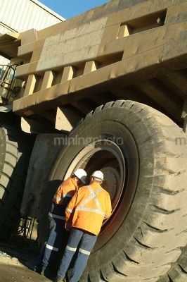 Two male workers servicing a large truck tyre at a mine site. - Mining Photo Stock Library