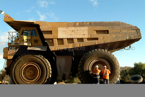 Two male workers inspecting a large truck tyre at a mine site. - Mining Photo Stock Library