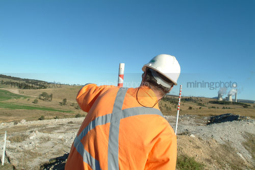 Mine manager inspecting open cut revegetation from a distance - Mining Photo Stock Library