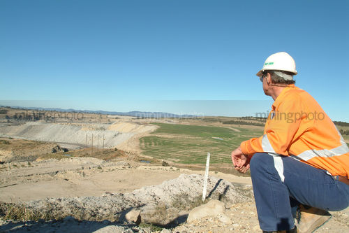 Mine manager inspecting open cut coal mine revegetation from a distance - Mining Photo Stock Library