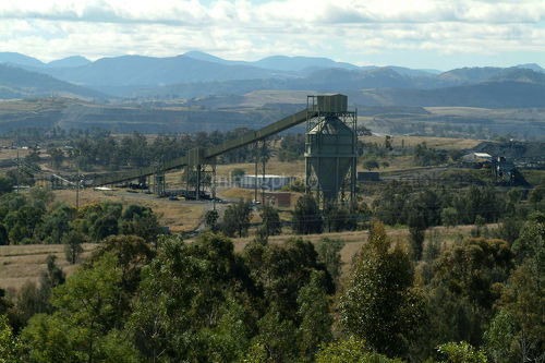 Distant shot of coal wash plant with rail and mountains in background.  good revegetation example in foreground. - Mining Photo Stock Library