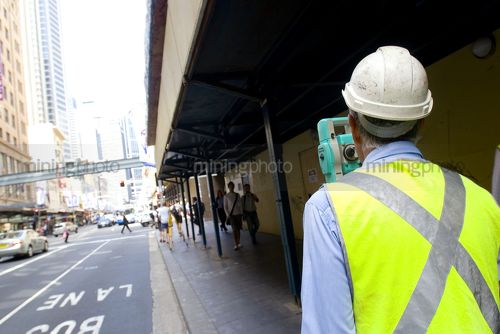 Surveyor in PPE working inner city roads. - Mining Photo Stock Library