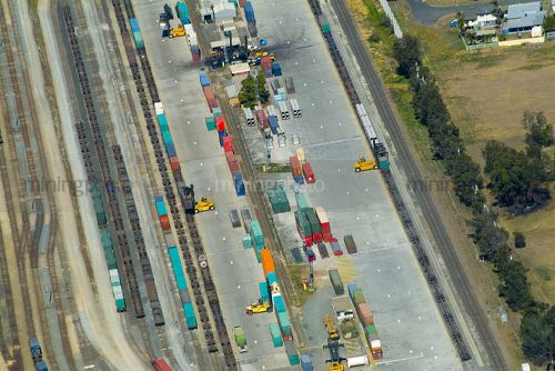 Ship containers being loaded by forklift onto heavy rail at transport yard. aerial shot - Mining Photo Stock Library