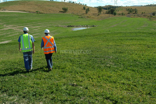 2 mine workers inspecting green revegetation on open cut coal mine site. - Mining Photo Stock Library