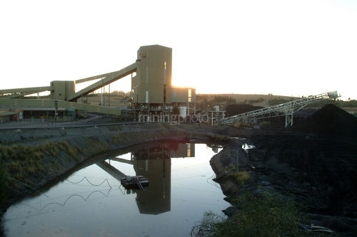 Sun setting over small coal wash plant. water storae dam in foreground - Mining Photo Stock Library