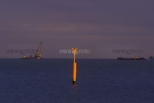 Pylon signal in shipping lane with barge, dredgre and ships in the background - Mining Photo Stock Library