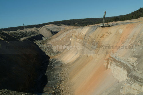 Open cut coal mine high walls with drill rig ready for blasting up top. coal seam down below. - Mining Photo Stock Library
