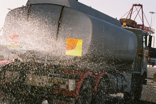 Water cart truck spraying on a construction site for dust control. - Mining Photo Stock Library