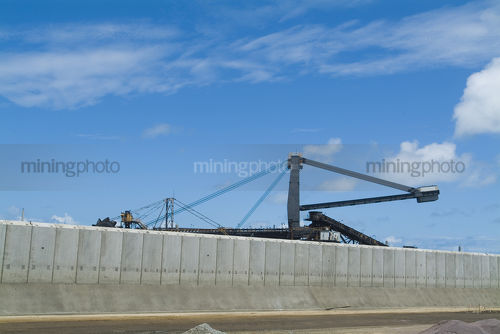 Coal stacker reclaimer at terminal with concrete precast bunding in foreground. - Mining Photo Stock Library