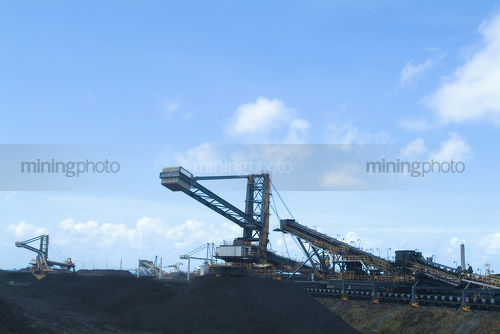 Coal reclaimers and stackers working stockpiles at coal terminal.  lots of stockpiling, conveyors adn heavy machinery. - Mining Photo Stock Library