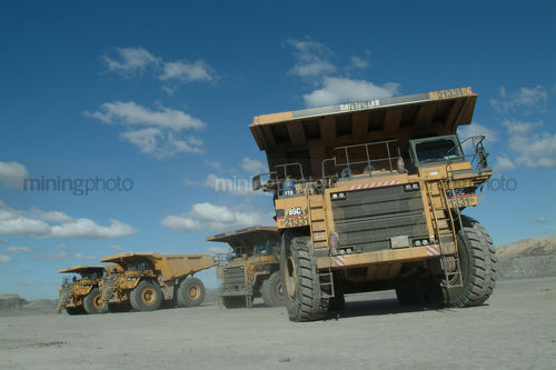 Large haul truck leaving the go line at the shift change.  shot from ground level to show size of truck. trucks in the background lined up. - Mining Photo Stock Library