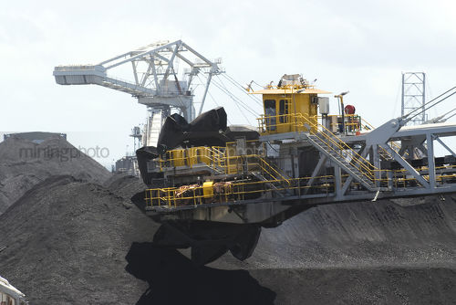 Close up shot of a coal reclaimer working on stockpiles at terminal. - Mining Photo Stock Library