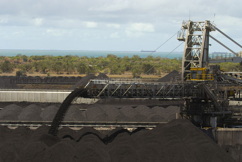 Coal pouring off the end of a reclaimer conveyor onto a stockpile at shipping terminal. - Mining Photo Stock Library