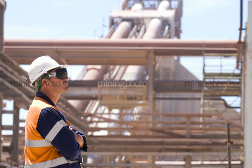 Process engineering worker looking to the right of camera frame with plant in the background.  good room for copy. - Mining Photo Stock Library