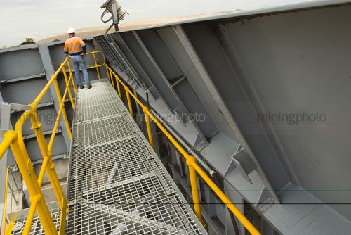 Mine site worker inspecting coal haul road from top of the dump hopper - Mining Photo Stock Library