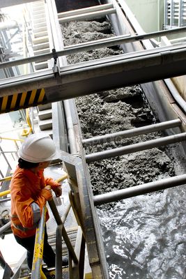 Mine engineer inspecting coal slurry inside a coal fired power station.  shot from above looking down.  vertical image. - Mining Photo Stock Library