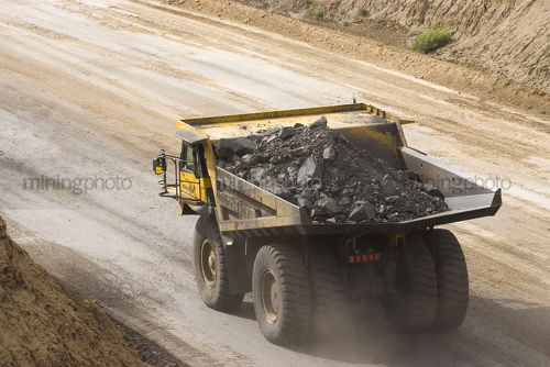 Loaded haul truck carrying overburden on haul road in open cut mine site. - Mining Photo Stock Library