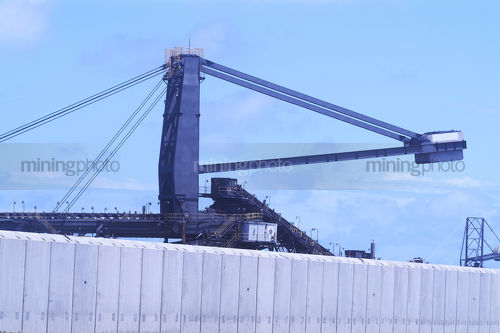 Close up of a reclaimer at coal terminal with pre cast bunding in foreground. - Mining Photo Stock Library