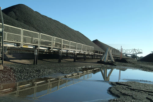 Coal reclaimer amongst many coal stockpiles. - Mining Photo Stock Library