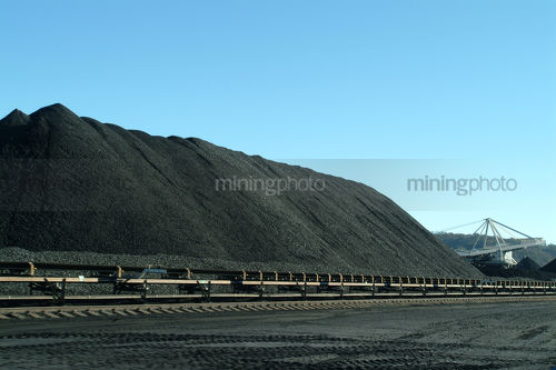 Coal reclaimer amongst many coal stockpiles. - Mining Photo Stock Library