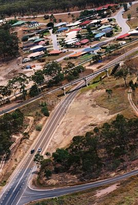 Cars on a 2 lane highway with railway bridge and residential subdivision in background. aerial shot - Mining Photo Stock Library