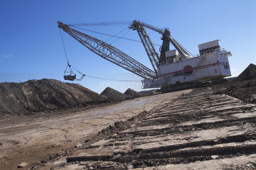 Dragline removing overburden in open cut coal mine.  shot from ground level looking along the tracks. - Mining Photo Stock Library
