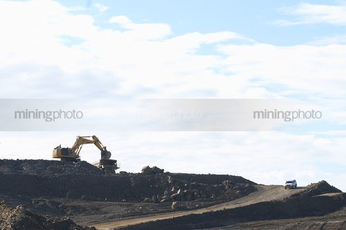Light vehicle driving haul road with excavator and haul truck. - Mining Photo Stock Library
