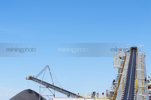 Coal conveyor and loader with coal stockpile to the side.  plenty of room for copy on this image. generic image. - Mining Photo Stock Library
