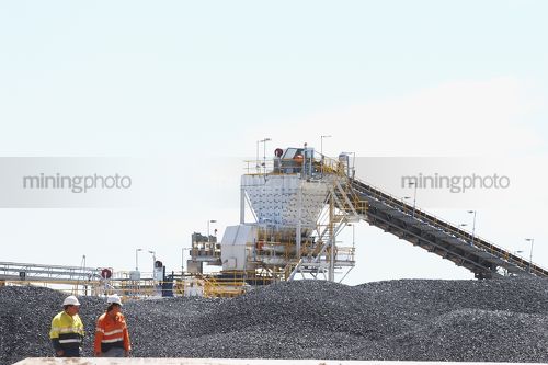 Two mine workers with coal stockpile and feeder in background - Mining Photo Stock Library