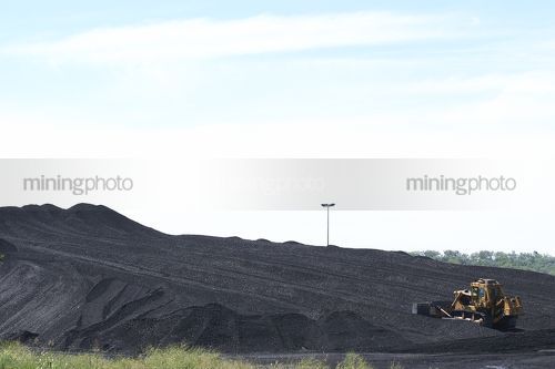 Wide shot of bulldozer stockpiling coal - Mining Photo Stock Library
