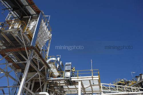 Engineer working on electrical cables and box at plant on mine site. - Mining Photo Stock Library