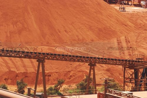 Large bauxite stockpile with loader conveyor in foreground - Mining Photo Stock Library