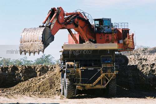 Large digger loading overburden into haul truck on opencut mine site - Mining Photo Stock Library