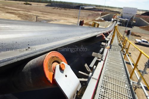 Close up of coal conveyor with plant out of focus in the background. - Mining Photo Stock Library