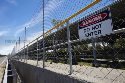 Do not enter sign on fence of an overland coal conveyor - Mining Photo Stock Library
