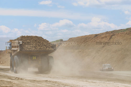 Haul truck loaded with overburden in the pit of an open cut coal mine.  light vehicle passing by. - Mining Photo Stock Library